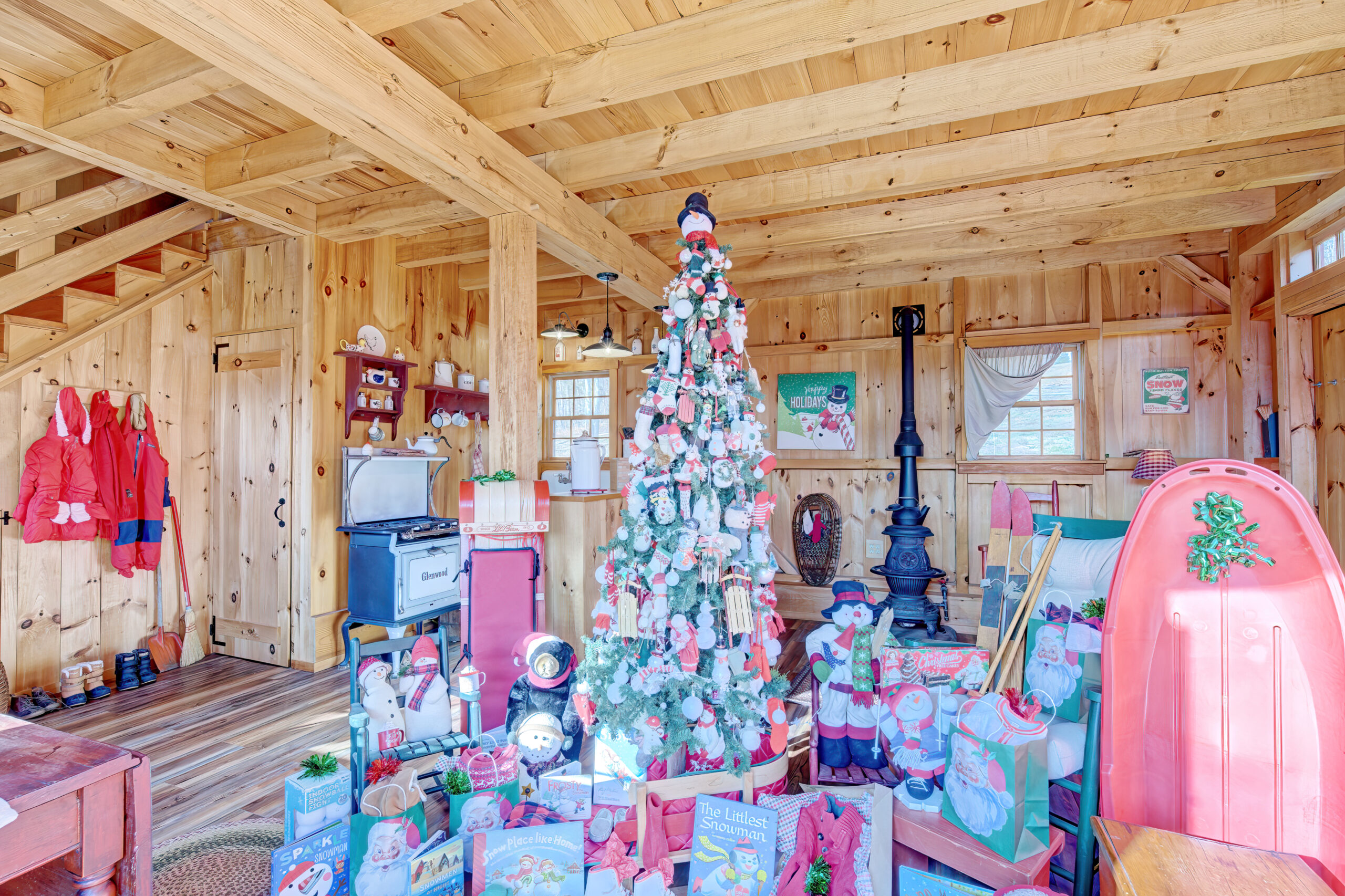 A snowman-themed Christmas tree inside of a Baker barn from Post and Beam Barns by Country Carpenters.